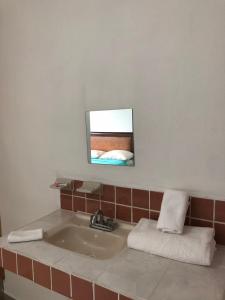 łazienka z umywalką i lustrem na ścianie w obiekcie Airport Sleepy Inn w mieście Cancún
