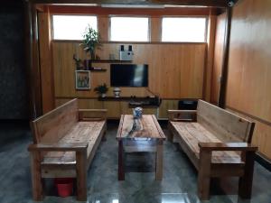 a living room with two benches and a tv at MeoVac Ethnic Homes in Mèo Vạc