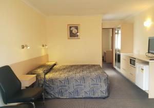 Habitación de hotel con cama y silla en Argyle Motor Lodge en Hobart