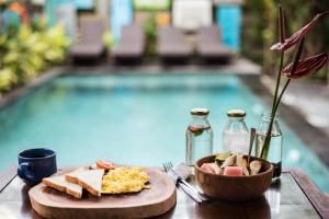un tavolo con un piatto di cibo accanto a una piscina di Arana Garden Ubud ad Ubud
