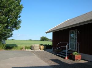 a brown building with a porch and a grass field at B&B Ströprodukter in Eslöv