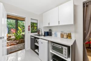 una cocina con armarios blancos y fregadero en Noosa Hinterland Retreat, en Tinbeerwah