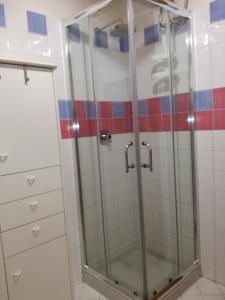 a glass shower in a bathroom with red and blue tiles at Le Ciaramire in Favignana