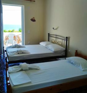 two beds in a room with a window at Billy's Amoudi Apartments in Amoudi +34 photos