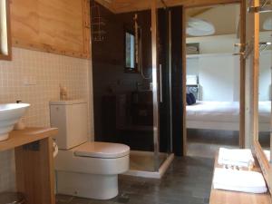 a bathroom with a toilet and a sink and a bedroom at Driftwood Bay of Fires in Binalong Bay