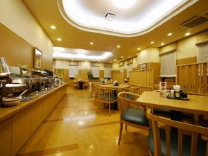 een restaurant met tafels en stoelen en een cafetaria bij Hotel Route-Inn Kitakami Ekimae in Kitakami