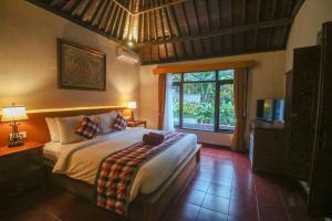 a bedroom with a bed and a large window at Aji Lodge Bungalow in Ubud