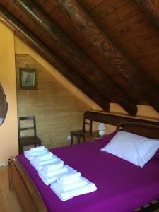 a bedroom with a purple bed with towels on it at Baita Emilia in Craveggia