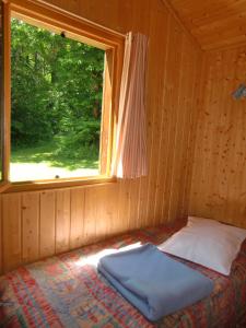 a bed in a wooden room with a window at Chalet en Auvergne -Pêche in Roumégoux