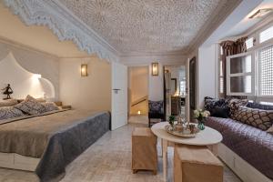 ein Schlafzimmer mit einem Bett, einem Sofa und einem Tisch in der Unterkunft Riad Star by Marrakech Riad in Marrakesch
