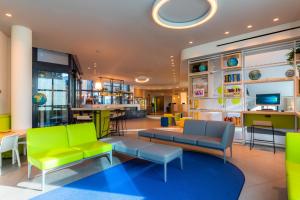 un vestíbulo con muebles verdes y azules y un bar en Airport Hotel Bergamo, en Bagnatica