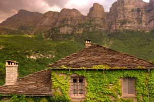 an ivy covered house with a mountain in the background at Avragonio in Papingo