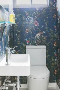 Banana palm luxury cottage في ديربان: حمام مع مرحاض وورق ورق جدران