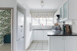 Banana palm luxury cottage في ديربان: مطبخ أبيض مع دواليب بيضاء ونافذة