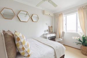 Banana palm luxury cottage في ديربان: غرفة نوم بيضاء مع سرير ونافذة