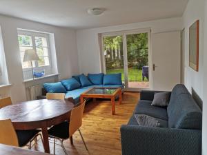 ein Wohnzimmer mit blauen Sofas und einem Tisch in der Unterkunft Beautiful House in Zehlendorf in Berlin