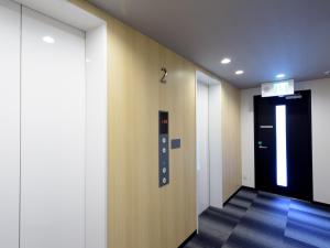a hallway with a black door and a black elevator at Tabist Hotel Asiato Namba in Osaka