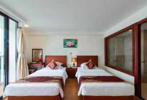 um quarto de hotel com duas camas e uma janela em Red Sun Nha Trang Hotel em Nha Trang