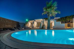 a swimming pool in front of a villa at night at Omnia Mykonos Boutique Hotel & Suites in Ornos