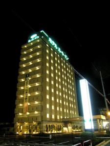 a large building with lights on it at night at Hotel Route-Inn Hanamaki in Hanamaki