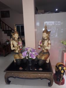 zwei Statuen auf einem Tisch mit Blumen in der Unterkunft SorotHouse in Jomtien Beach