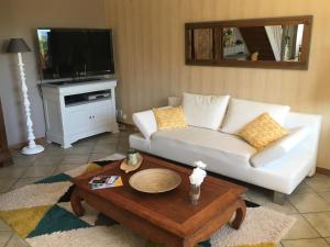 Sala de estar con sofá blanco y mesa de centro en La Casa Cantarana, en Le Teich