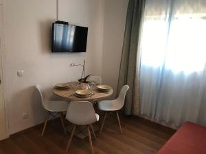 a dining room table with chairs and a television on the wall at Apartment Kamenica in Kornić