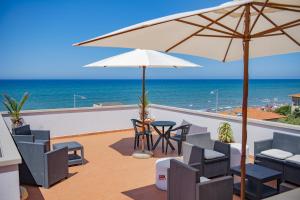 eine Terrasse mit einem Tisch, Stühlen und einem Sonnenschirm in der Unterkunft Hotel del Sole in San Vincenzo
