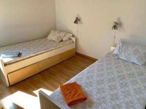 2 camas en una habitación pequeña con 2 lámparas en Casa Mya. A Modern Duplex in the Spanish Pyrenees, en Aso de Sobremonte