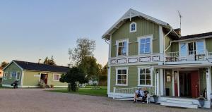 twee mensen die voor een groen huis zitten bij Råda Hotel in Hagfors