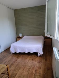 a bedroom with a white bed and wooden floors at Colline de la bergerie in Cambo-les-Bains