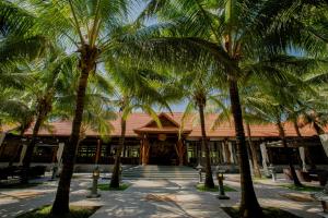 a group of palm trees in front of a building at Seava Ho Tram Beach Resort in Ho Coc