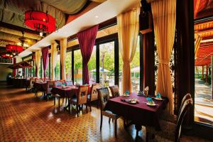 a dining room with tables and chairs and windows at Seava Ho Tram Beach Resort in Ho Coc