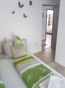 - un lit blanc avec des draps verts et des papillons sur le mur dans l'établissement Pensiunea Doce, à Vişeu de Sus