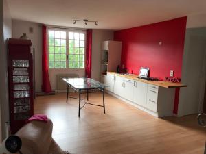 a kitchen with a glass table and a red wall at La pause nuitonne in Nuits-Saint-Georges