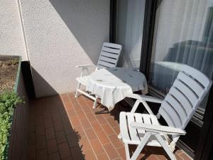 2 sillas blancas y una mesa en el balcón en Ferienwohnung Voges, en Bad Lauterberg