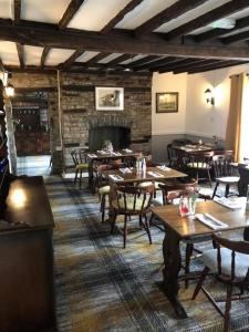 restauracja z drewnianymi stołami i krzesłami oraz kominkiem w obiekcie The Griffin Llyswen w mieście Brecon