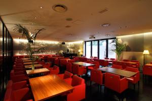 ein Restaurant mit roten Stühlen und Holztischen in der Unterkunft Oriental Hotel Hiroshima in Hiroshima