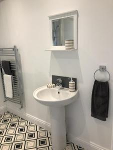 a white bathroom with a sink and a mirror at Bay View Apartment in Newbiggin-by-the-Sea