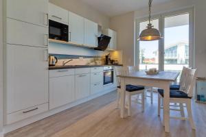 a kitchen with white cabinets and a table with chairs at AHOI in Glowe