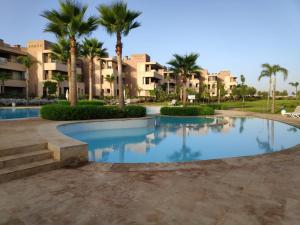 - une piscine dans un complexe avec des palmiers et des bâtiments dans l'établissement Magnifique appart vue sur golf, à Marrakech