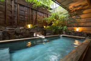 an indoor pool with a stone wall and a swimming poolitures at Miyajima Grand Hotel Arimoto in Miyajima