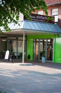 a green building with a blue awning and a sign at Fehren einfach gut in Lingen