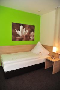 a bedroom with a green wall with a bed and a table at Fehren einfach gut in Lingen