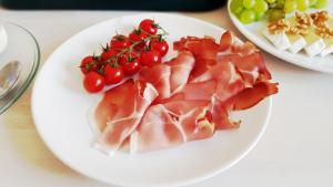a plate of food with ham and tomatoes and grapes at Kamienica Bankowa Residence in Poznań