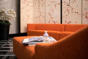an orange couch with a table with books and a bottle at V Hotel Lavender in Singapore