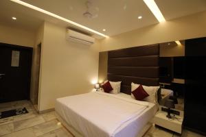 1 dormitorio con 1 cama blanca grande con almohadas rojas en Hotel Shivam, en Pune