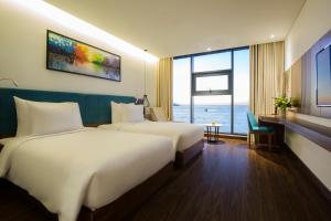 A bed or beds in a room at Maximilan Danang Beach Hotel