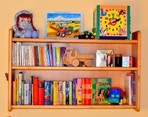 un estante de libros con libros y juguetes. en Bauernhof König en Zwiesel