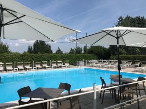 a swimming pool with tables and chairs and an umbrella at The Riverside Suite in Mira
